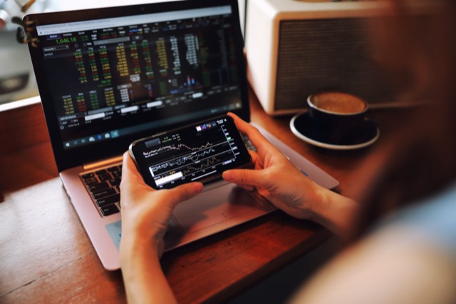 Trader checking the market on a laptop and phone